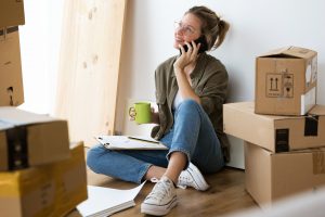 young woman talking on her mobile phone while surrounded by boxes