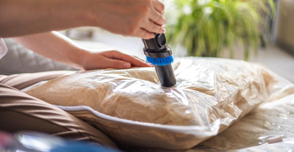 person using vacuum to seal cushion in vacuum seal bag